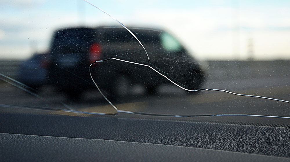 View through cracked glass on the road, stone smashed car windshield
